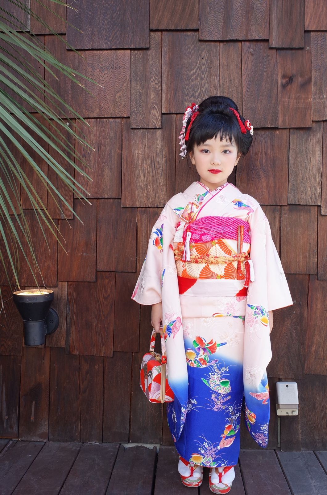 杉板の壁の前に立つ七五三の着物姿の女の子