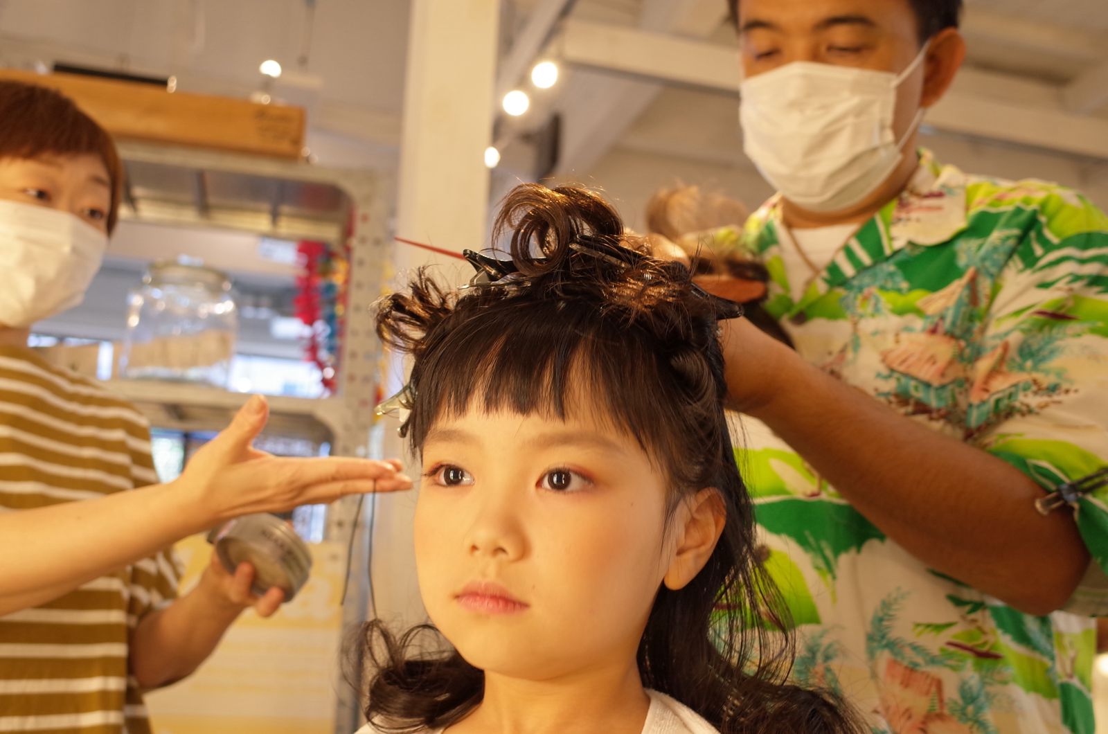 アロハシャツの美容師に髪を結ってもらい笑う女の子
