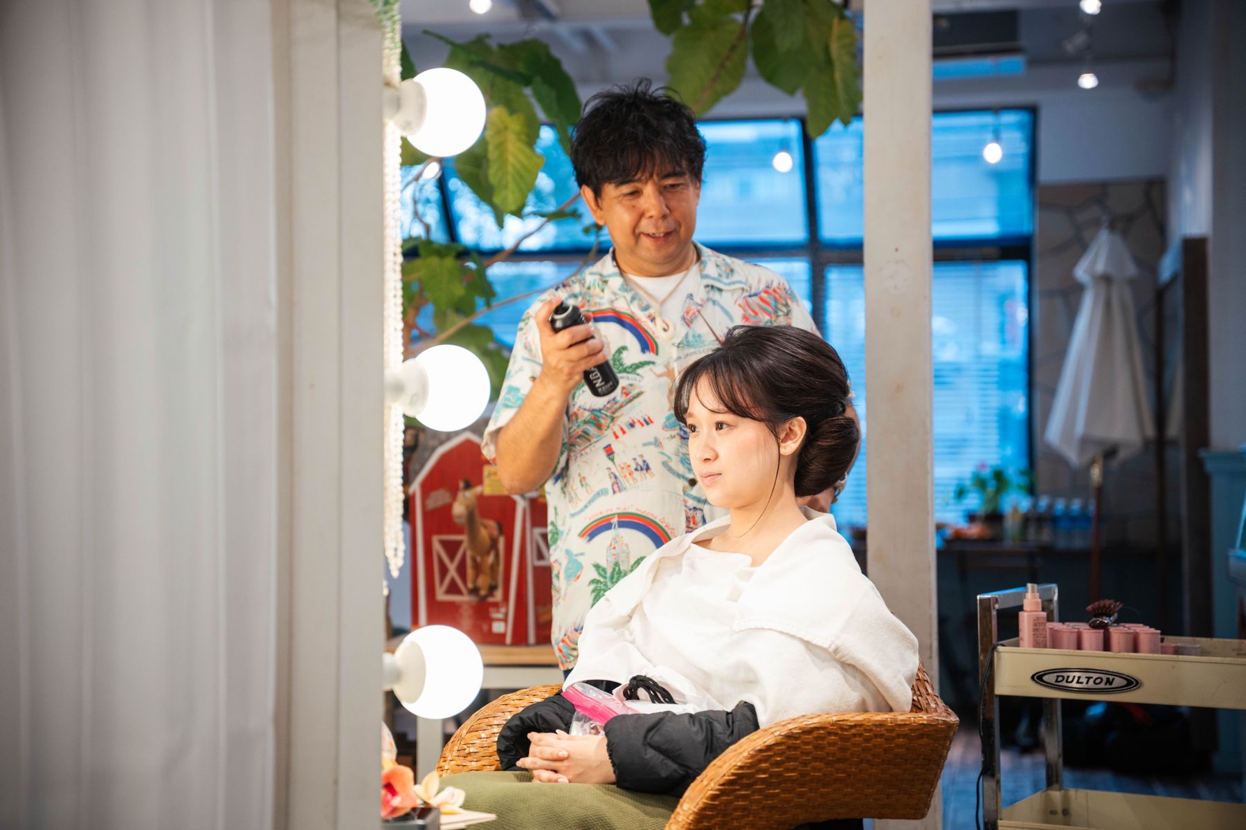 ハリウッドミラーの前でヘアセットを仕上げる美容師