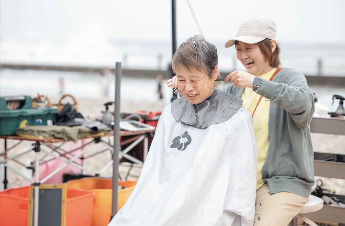 海辺のイベントで笑いながら髪を切るKiyo