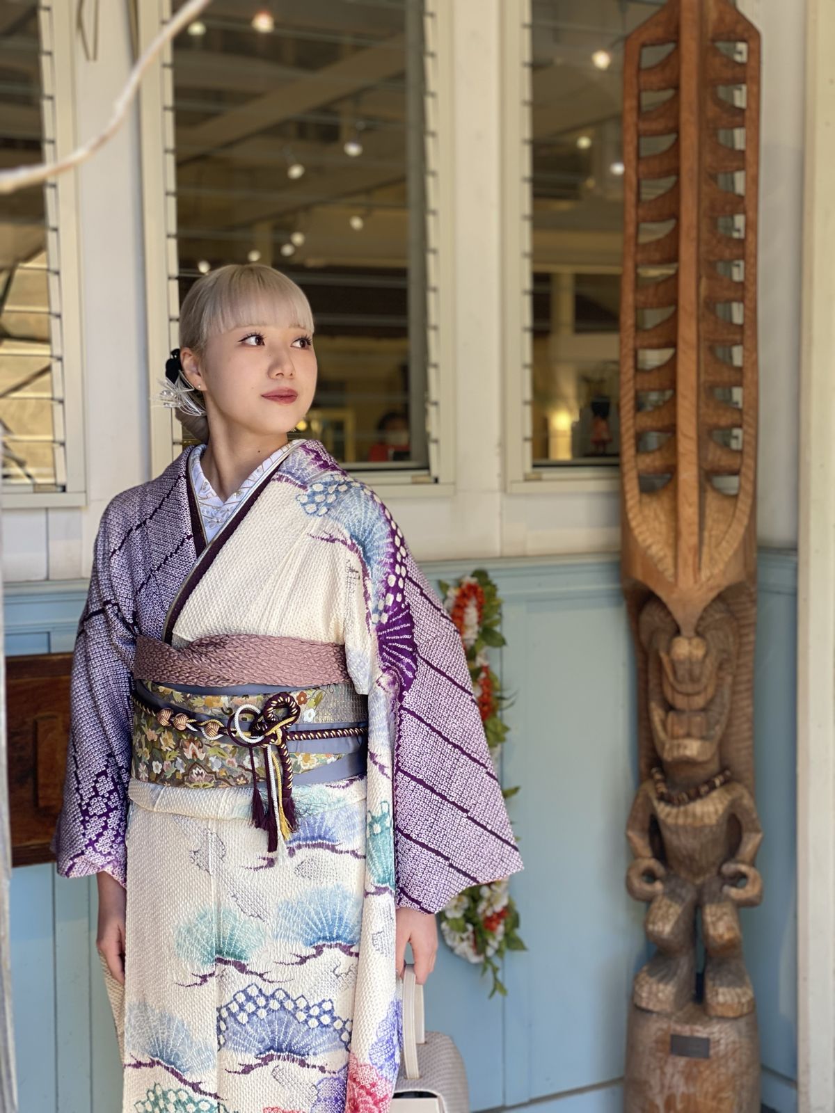 ティキの彫刻の横に立つ絞りの振袖姿の女性